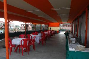 a restaurant with red chairs and tables on a balcony at Park Palace Hotel in Kolkata