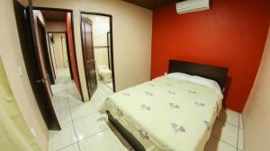 1 dormitorio con cama y pared roja en Arenal Red, en Fortuna