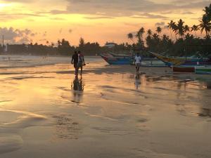 a group of people walking on the beach at sunset at Weligama Ocean Breeze in Weligama