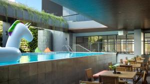 a swimming pool with tables and chairs and a restaurant at ARTOTEL Yogyakarta in Yogyakarta