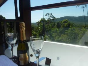 Una botella de vino y dos copas en una mesa. en Daintree Holiday Homes - Yurara, en Cow Bay