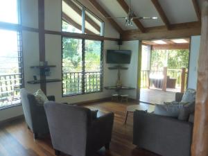 a living room with couches and a flat screen tv at Daintree Holiday Homes - Yurara in Cow Bay