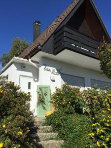 una casa blanca con una puerta verde y algunos arbustos en Haus Nicole, en Herrischried