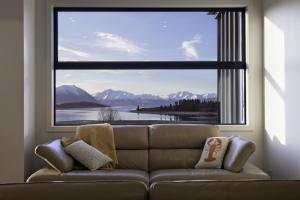 a couch in a living room with a large window at Ranginui At Lake Tekapo in Lake Tekapo