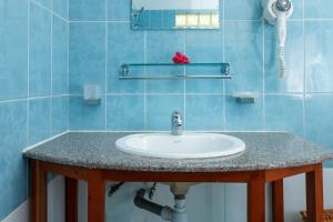 baño con lavabo y azulejos azules en Captain's Villa en Takamaka