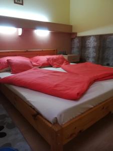 a large bed with red sheets and pillows on it at Czermann Panzió és Étterem in Oroszlány