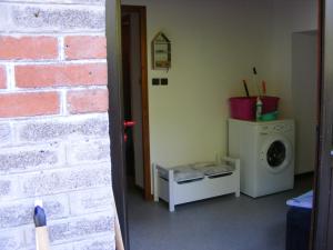 a laundry room with a washing machine next to a brick wall at Les mimosas in La Bresse