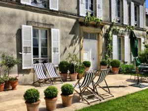 três cadeiras sentadas em frente a uma casa com plantas em Clos de Bellefontaine B&B em Bayeux
