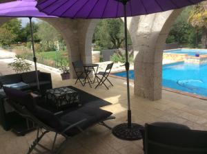 a patio with chairs and an umbrella next to a pool at Le Bois de Montpouillan in Montpouillan