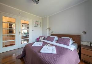 a bedroom with a large bed with purple sheets and towels at City Center Boutique Apartment in Warsaw