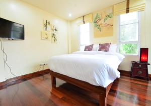 a bedroom with a large bed and a flat screen tv at Ayi Home in Bangkok