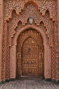 una grande porta in legno in una camera con pavimento piastrellato di Riad Ouarzazate a Ouarzazate