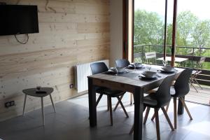a dining room with a table and chairs and a large window at Le chalet des Pierres in Viuz-en-Sallaz