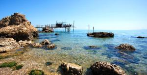 uma praia com pedras e um cais na água em La Taverna del Marchigiano em SantʼEusanio del Sangro