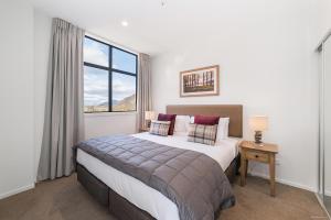 Un dormitorio con una cama grande y una ventana en Executive 2 Bedroom Apartment Remarkables Park en Queenstown