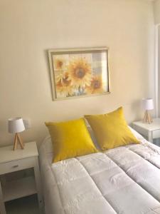 Un dormitorio con una cama con almohadas amarillas y una pintura en Alquiler temporario tucuman barrio norte 1 en San Miguel de Tucumán