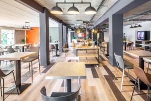 an empty restaurant with tables and chairs at Carré Pau Airport Hôtel in Serres-Castet