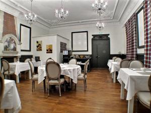 a dining room with white tables and chairs and chandeliers at Hôtel 19'Cent in Le Creusot