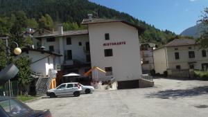 une voiture blanche garée devant un bâtiment dans l'établissement Hotel Galles, à Paluzza