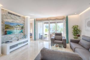 sala de estar con sofá y TV en Hanami Alcazaba Beach Penthouse, en Estepona