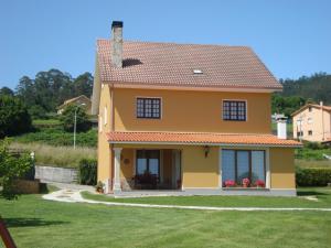 a small yellow house with a grass yard at Casas Cuncheiro in Canduas