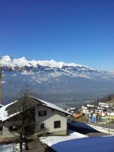 a town with snow covered mountains in the background at Hotel Restaurant Kulm in Triesenberg