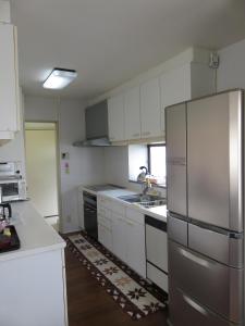 a kitchen with white cabinets and a stainless steel refrigerator at Hostel Kamakura in Kamakura