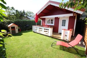 a red house with a chair in a yard at Blockbohlenhaus Plau am See in Plau am See
