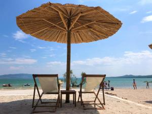 due sedie e un ombrellone su una spiaggia di Camping Vransko jezero - Crkvine a Pakoštane