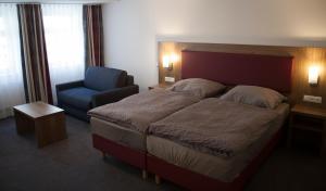 1 dormitorio con 1 cama grande y 1 silla azul en La Flamme Wertheim garni, en Wertheim