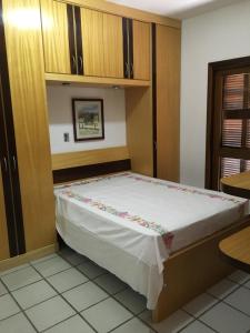 uma cama num quarto com armários de madeira em Excelente Casa em Bombas em Bombinhas