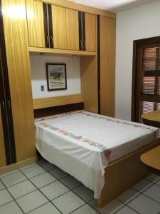 a bed in a room with wooden cabinets at Excelente Casa em Bombas in Bombinhas