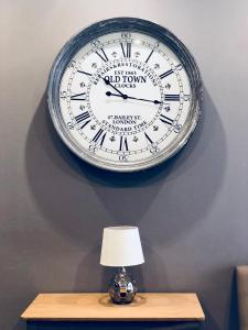 a clock on a wall above a table with a lamp at Holiday townhouse in Sliema centre in Sliema