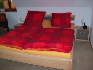 a bed with a red comforter and two red pillows at Zum-Luetten-Leuchtturm in Glowe