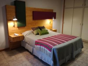 Schlafzimmer mit einem großen Bett mit einem Kopfteil aus Holz in der Unterkunft Hosteria ACA al Sur in Villa La Angostura