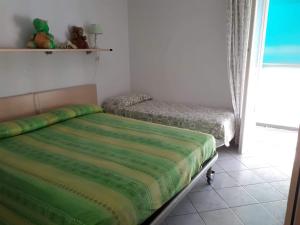 een slaapkamer met een bed met een groen dekbed bij appartamento vicino al mare Alassio in Alassio