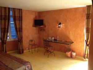 a bedroom with a desk and a tv on the wall at Hotel L'Astrolabe in Oloron-Sainte-Marie