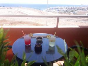 einen Tisch mit Getränken auf einem Balkon mit Blick auf den Strand in der Unterkunft Burrero Seasight in Ingenio