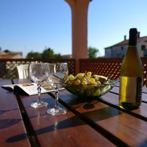 a table with a bowl of fruit and a bottle of wine at Anica Apartment in Banjole