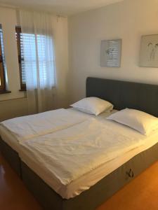 ein Bett mit weißer Bettwäsche und Kissen in einem Schlafzimmer in der Unterkunft Apartment Roxheim in Roxheim