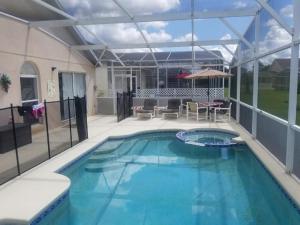 einen großen Pool mit Terrasse und Sonnenschirm in der Unterkunft Pool Home 15 Minutes From Disney in Davenport