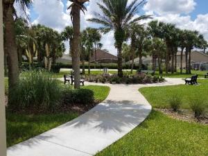 a walkway in a park with benches and palm trees at Pool Home 15 Minutes From Disney in Davenport