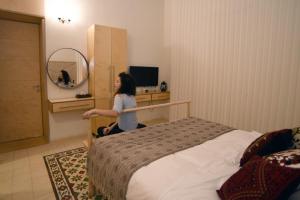 une femme assise à côté d'un lit dans une pièce dans l'établissement El Sayed House b&b, à Acre