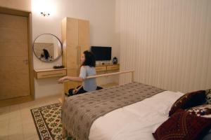 a woman sitting next to a bed in a room at El Sayed House in Acre