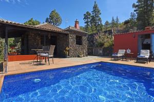 a pool with chairs and a table and a house at Casa Antonia in Tijarafe