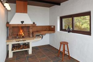 a kitchen with a fireplace and a stool and a window at Casa Antonia in Tijarafe