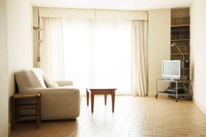ein Wohnzimmer mit einem Stuhl und einem TV in der Unterkunft Apartment Medes Platja in L'Estartit