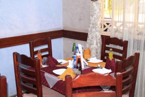 einem Holztisch mit Stühlen und einem Tisch mit Flaschen darauf in der Unterkunft Hotel Marvin in Nakuru