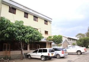 zwei Autos auf einem Parkplatz vor einem Gebäude geparkt in der Unterkunft Hotel Marvin in Nakuru