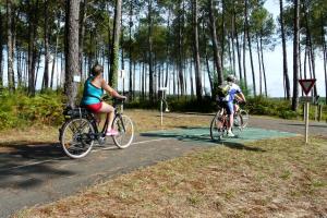 two people riding bikes on a road near trees at Blue Ocean in Moliets-et-Maa